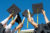 Diplomas and graduation hats are held up to the sky